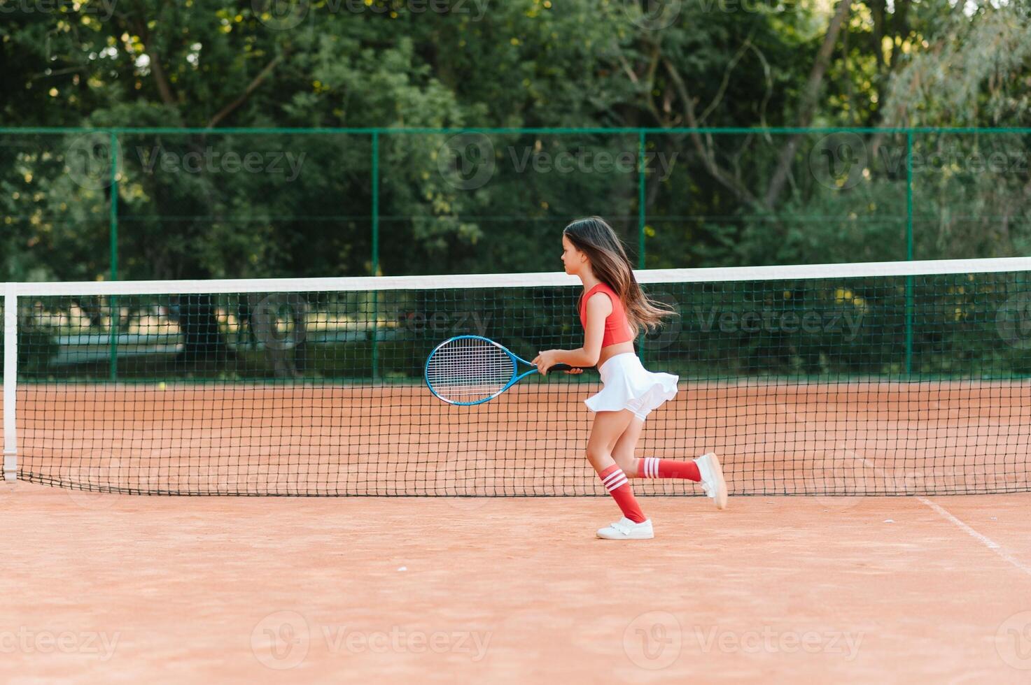 Child playing tennis on outdoor court. Little girl with tennis racket and ball in sport club. Active exercise for kids. Summer activities for children. Training for young kid. Child learning to play photo