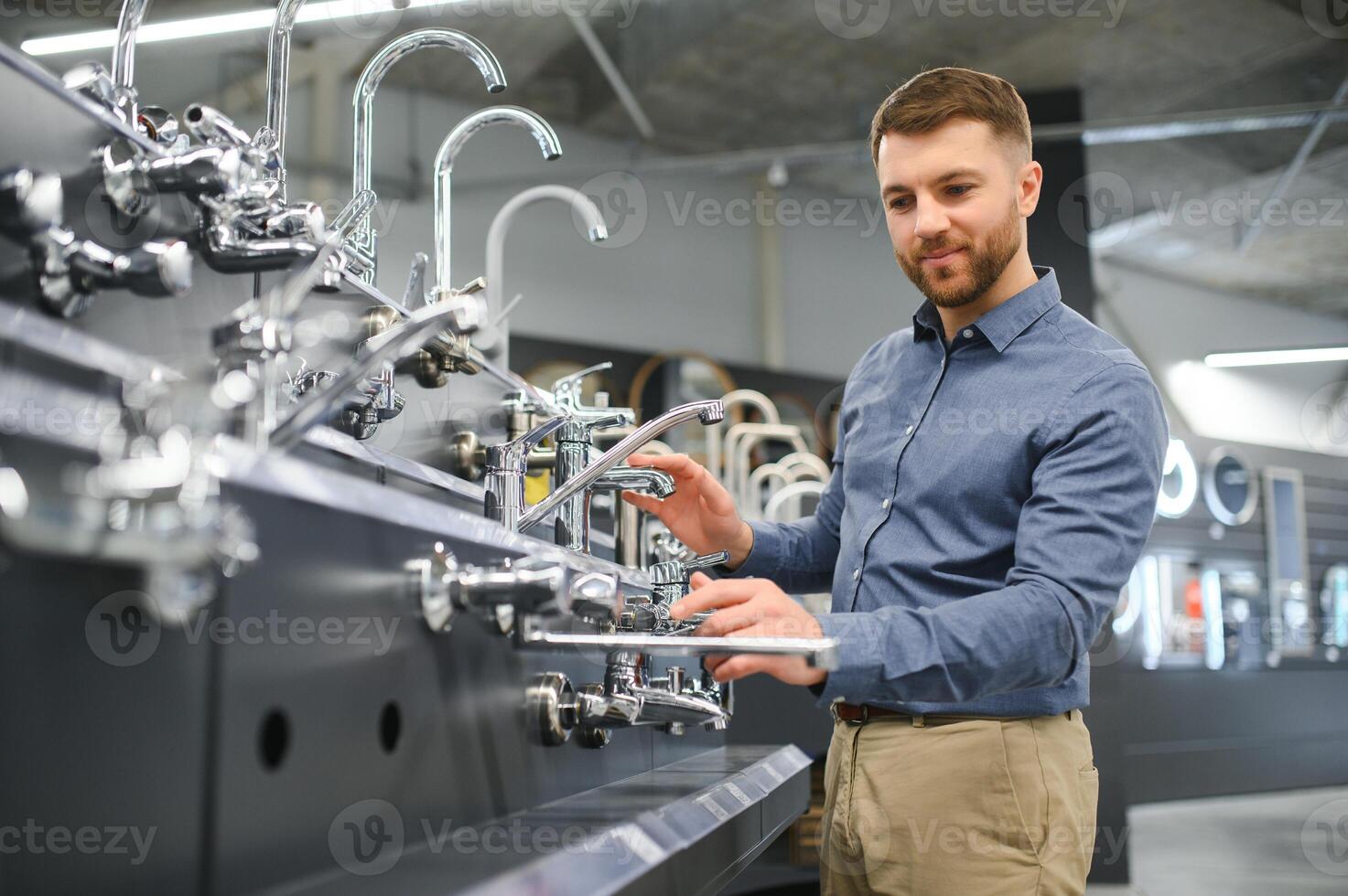 A large selection of water faucets. Man chooses a products in a sanitary ware store photo