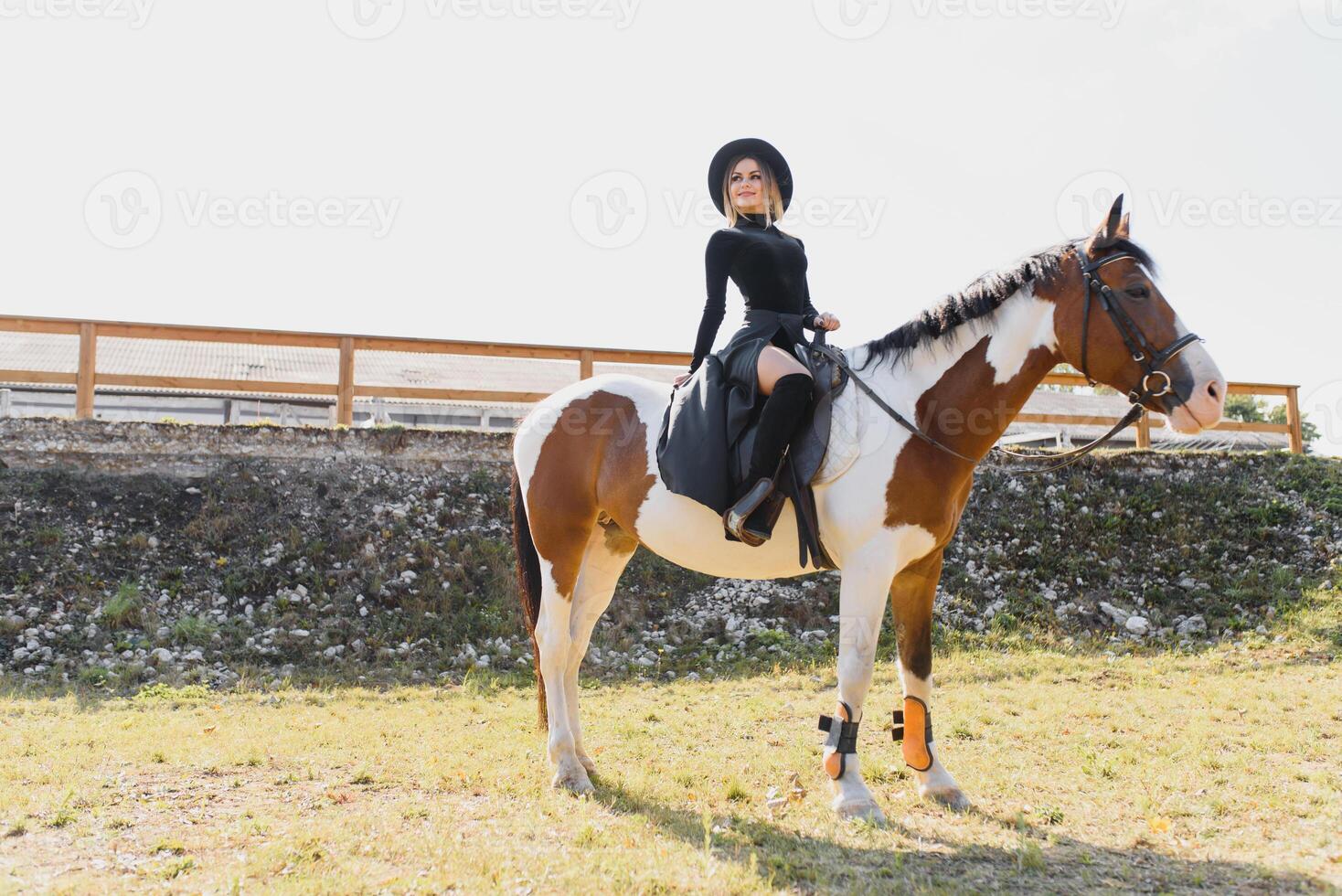 Happy fashionable young woman posing with a horse on the beach photo