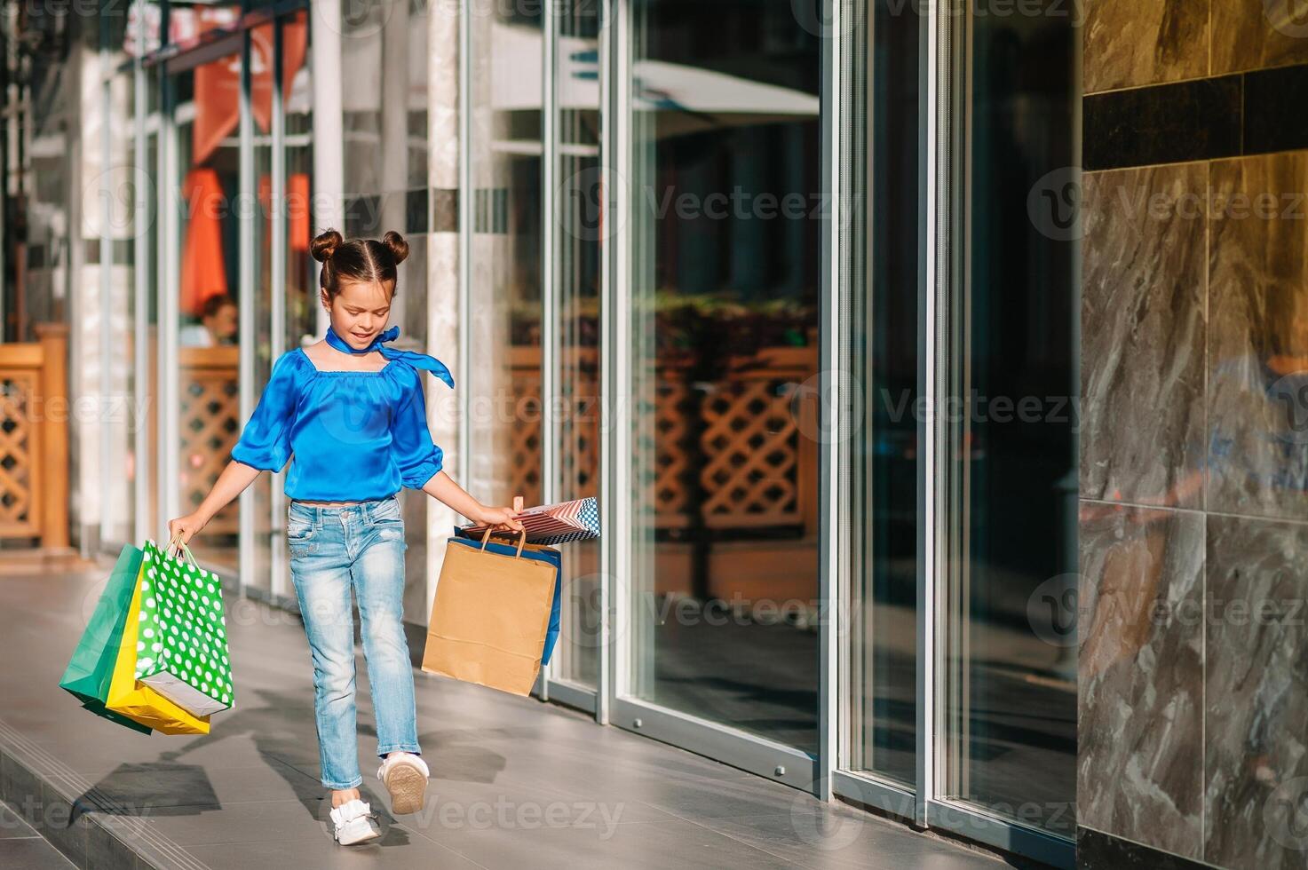 Portrait of beautiful smiling little girl wearing with shopping bag outdoors photo