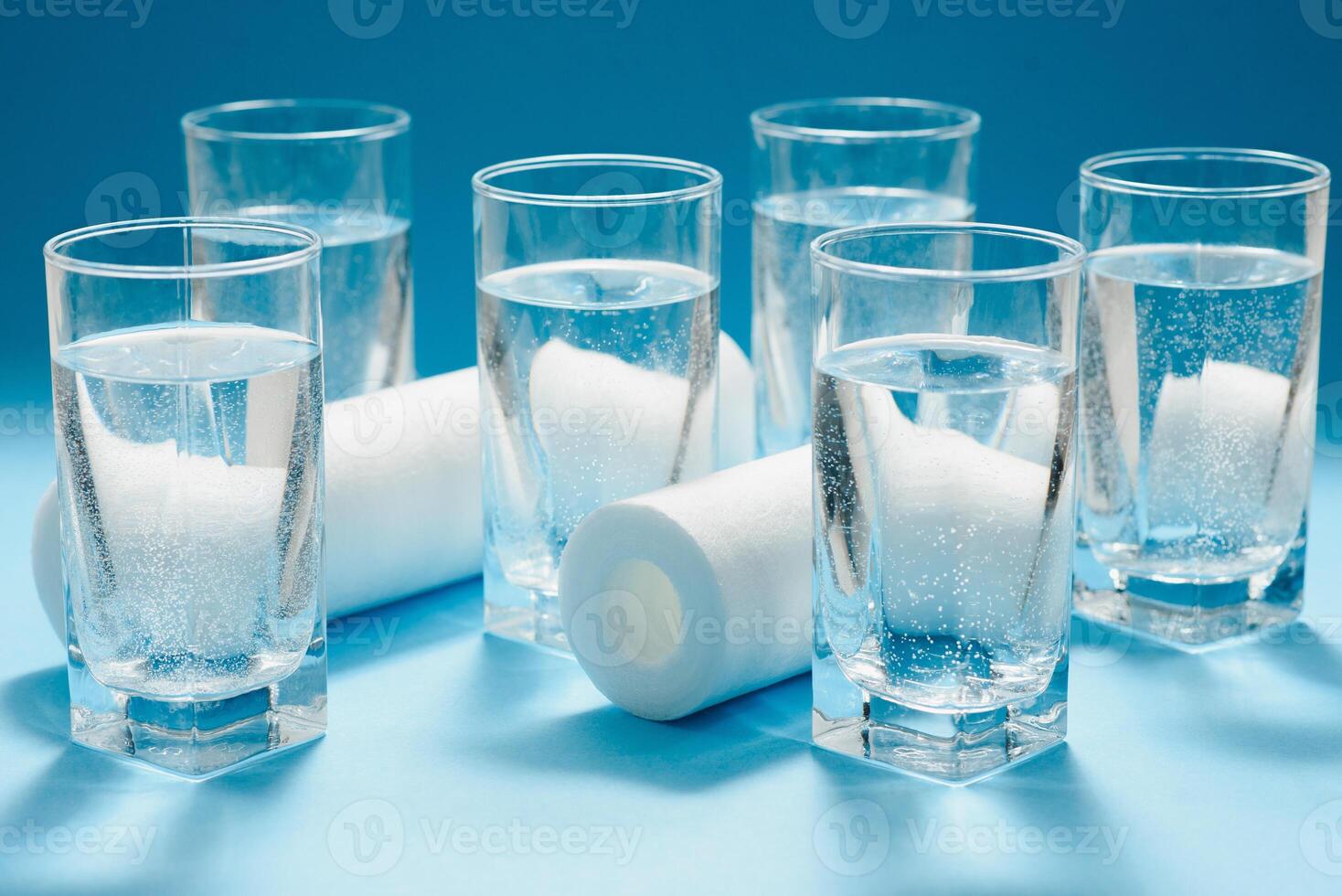 Water filters. Carbon cartridges and glasses on a blue background. Household filtration system. photo