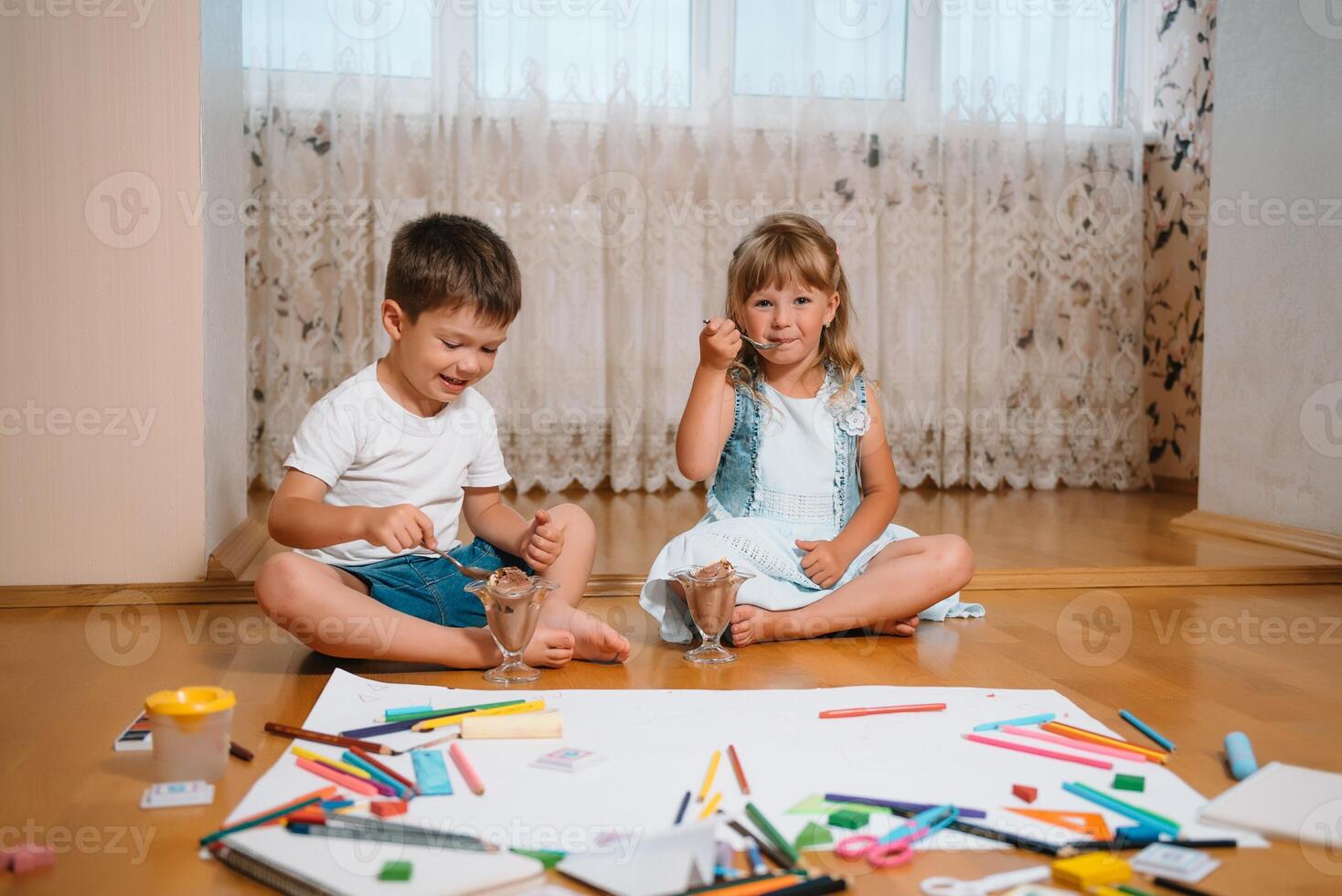 Kids drawing on floor on paper. Preschool boy and girl play on floor with educational toys - blocks, train, railroad, plane. Toys for preschool and kindergarten. Children at home or daycare. photo