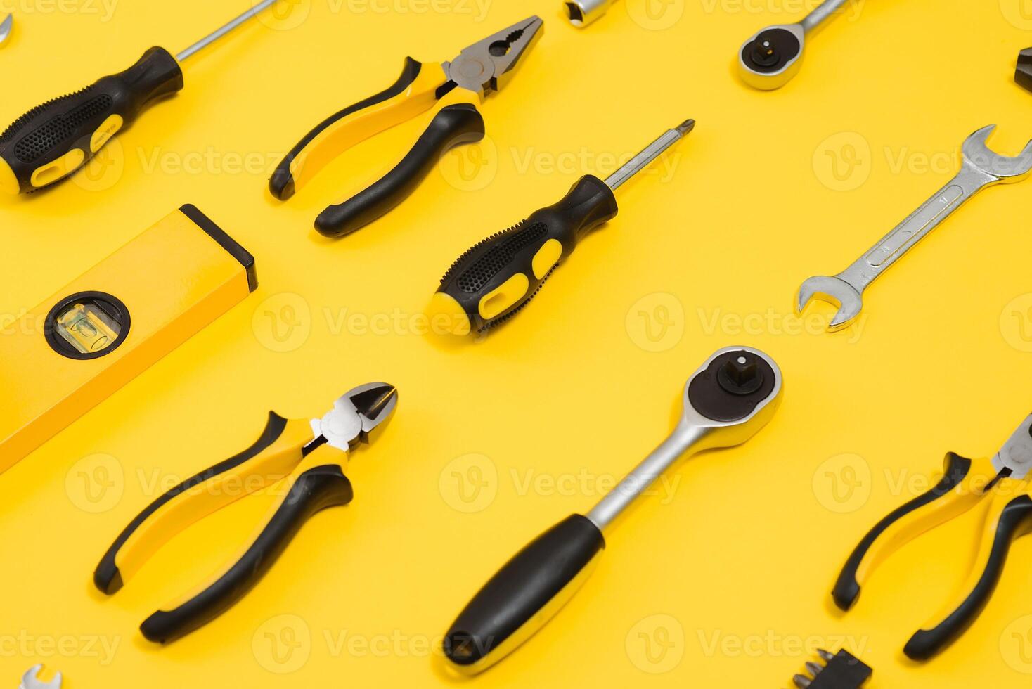 Yellow and black handy tools pilers and screwdriver isolated on yellow background. photo