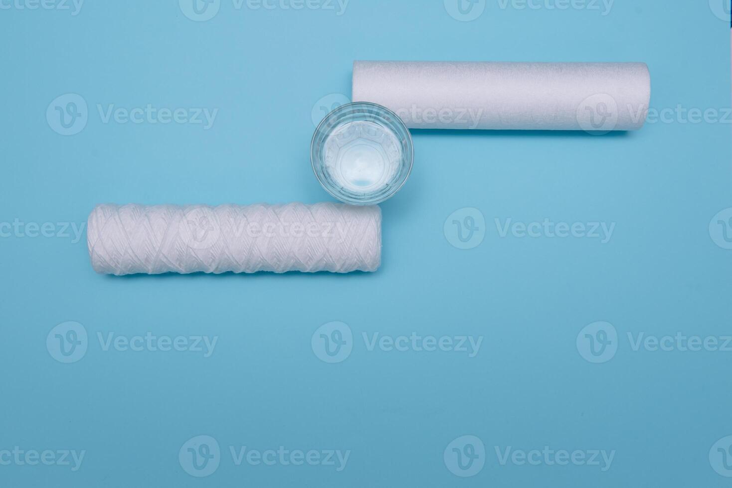 Water filters. Carbon cartridges and a glass on a blue background. Household filtration system. photo
