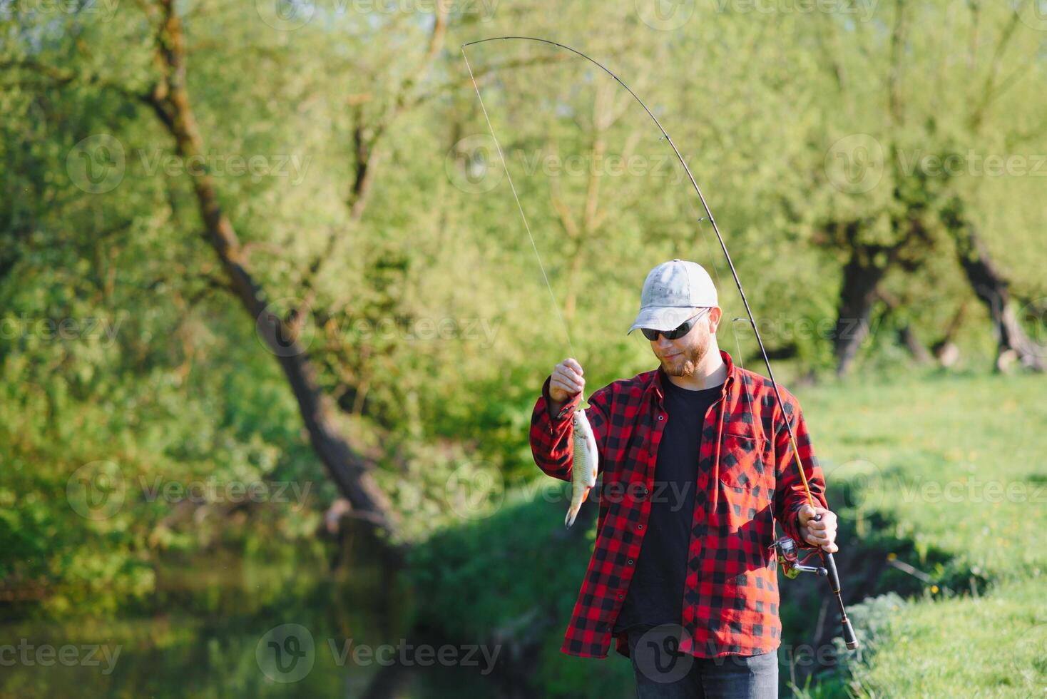 fisherman by the river with a catch of fish. Man fisherman holds in hand fish. photo