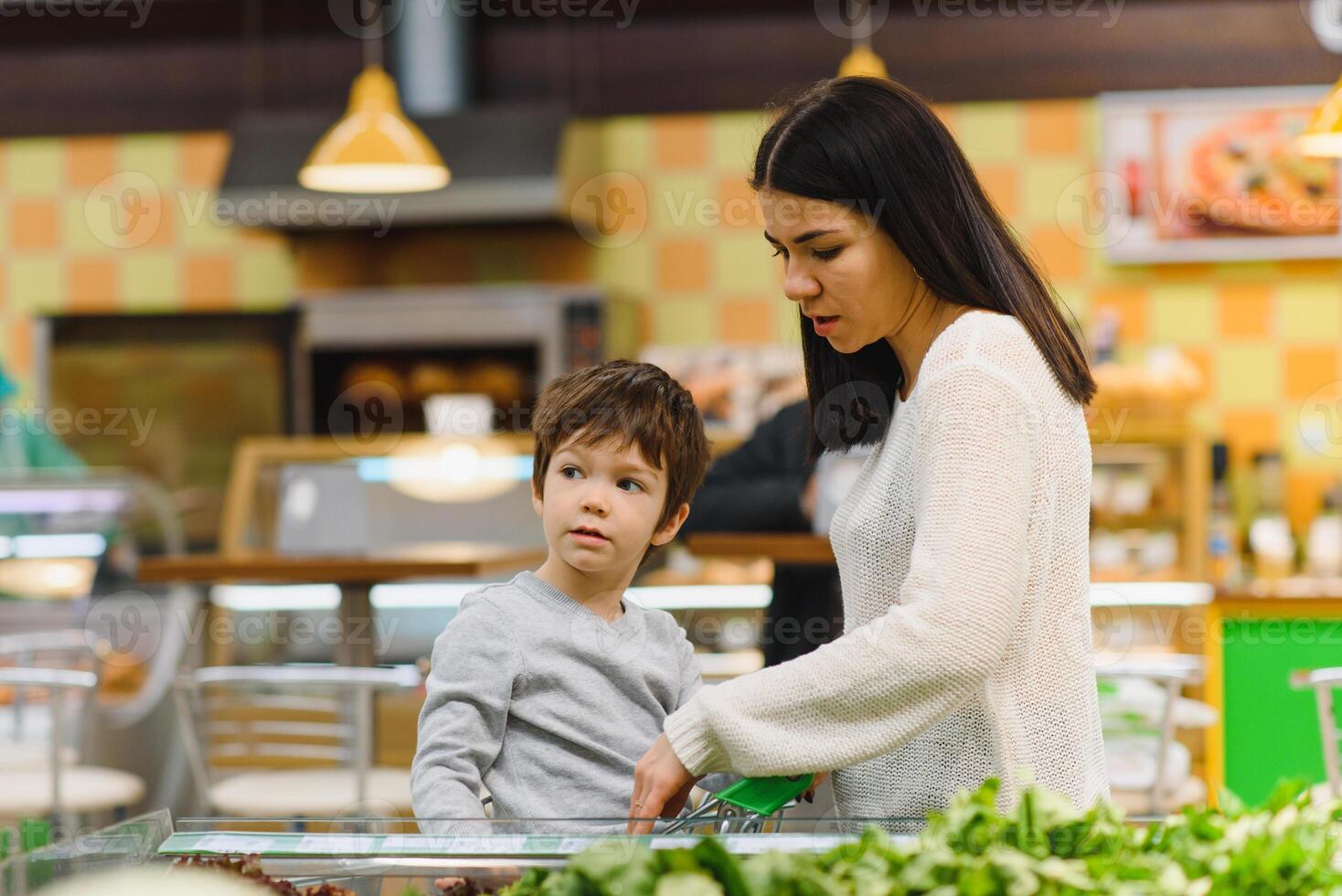 woman and child boy during family shopping with trolley at supermarket photo