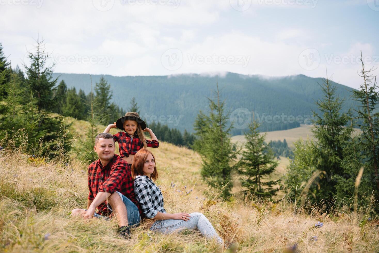 Family of three people rest in the mountains. They sat down to rest, drink water after a hard climb to the mountain. They are tired but happy. photo