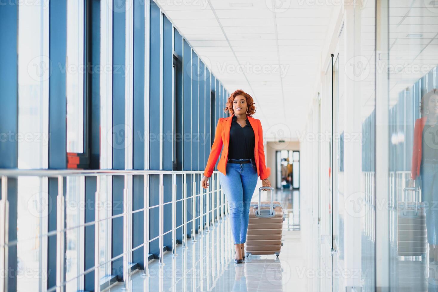 Full length side portrait of young black woman walking with suitcase in airport photo