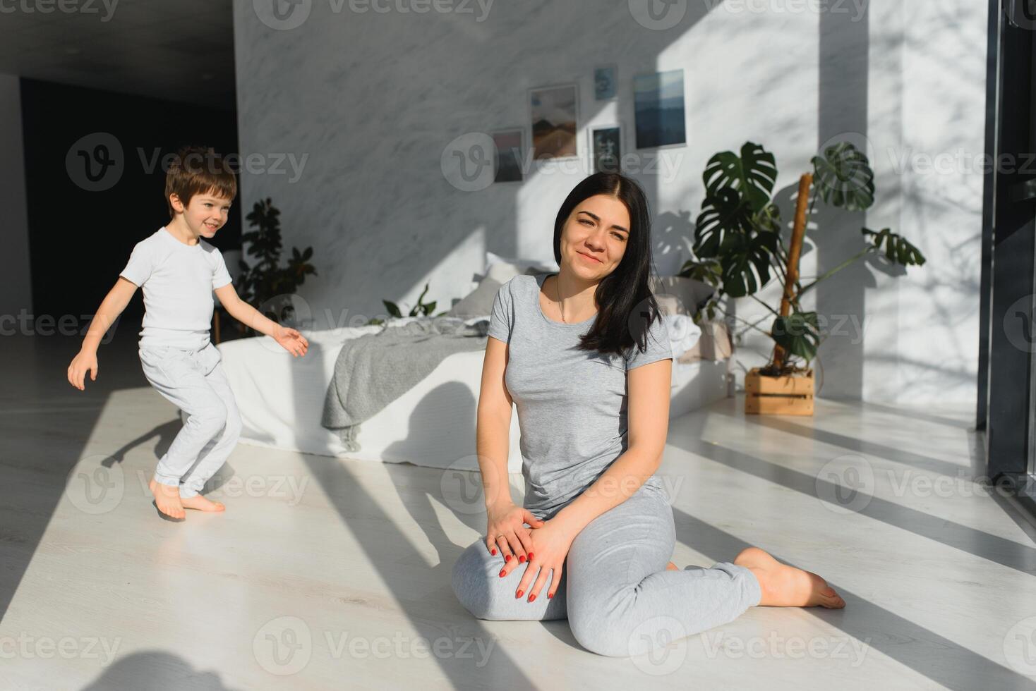 happy woman having fun with adorable son in pajamas in bedroom on mothers day. photo