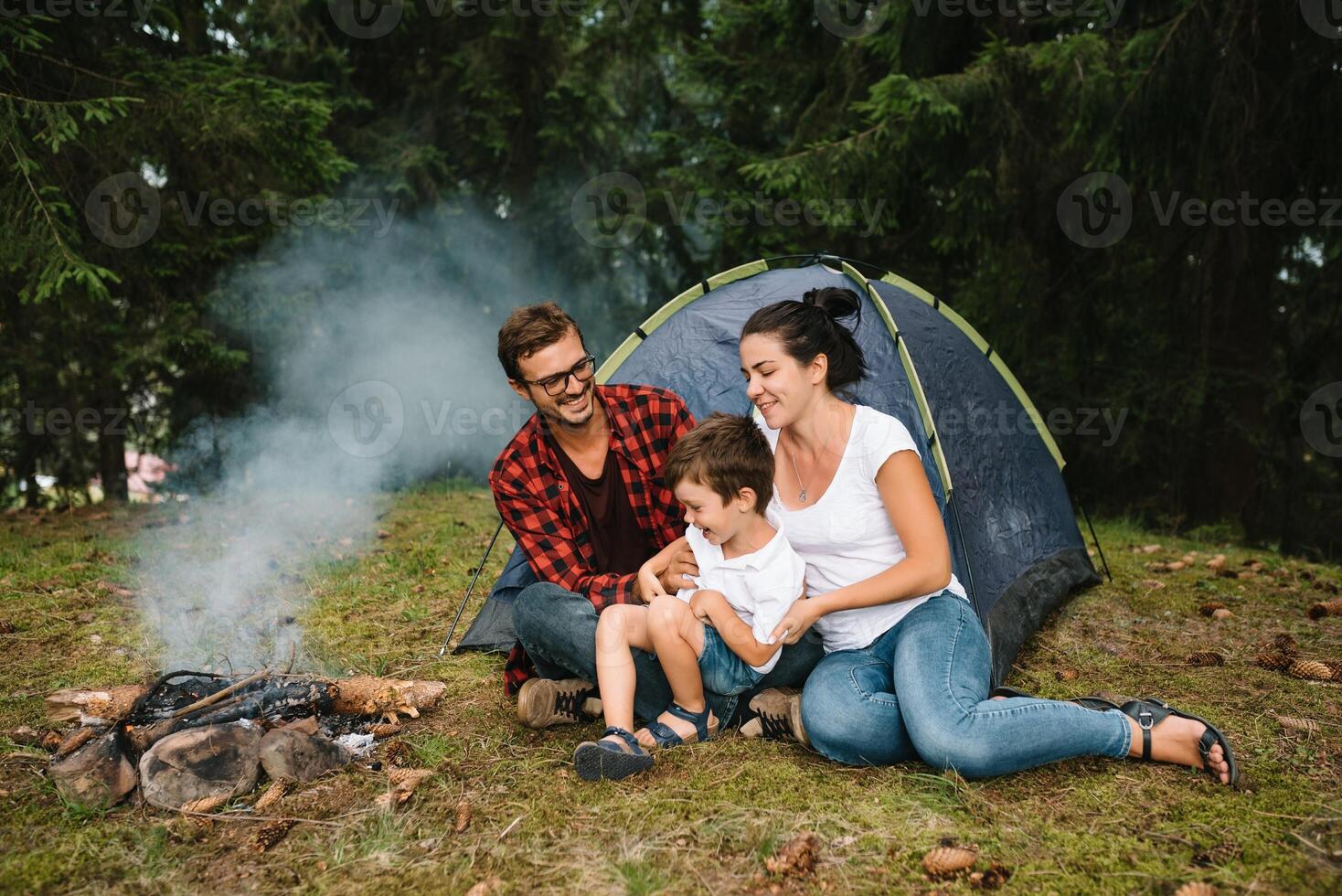 Family near the fire in the forest. Parent with child on a tent background. National Park. Hike with children. Active summer holidays photo