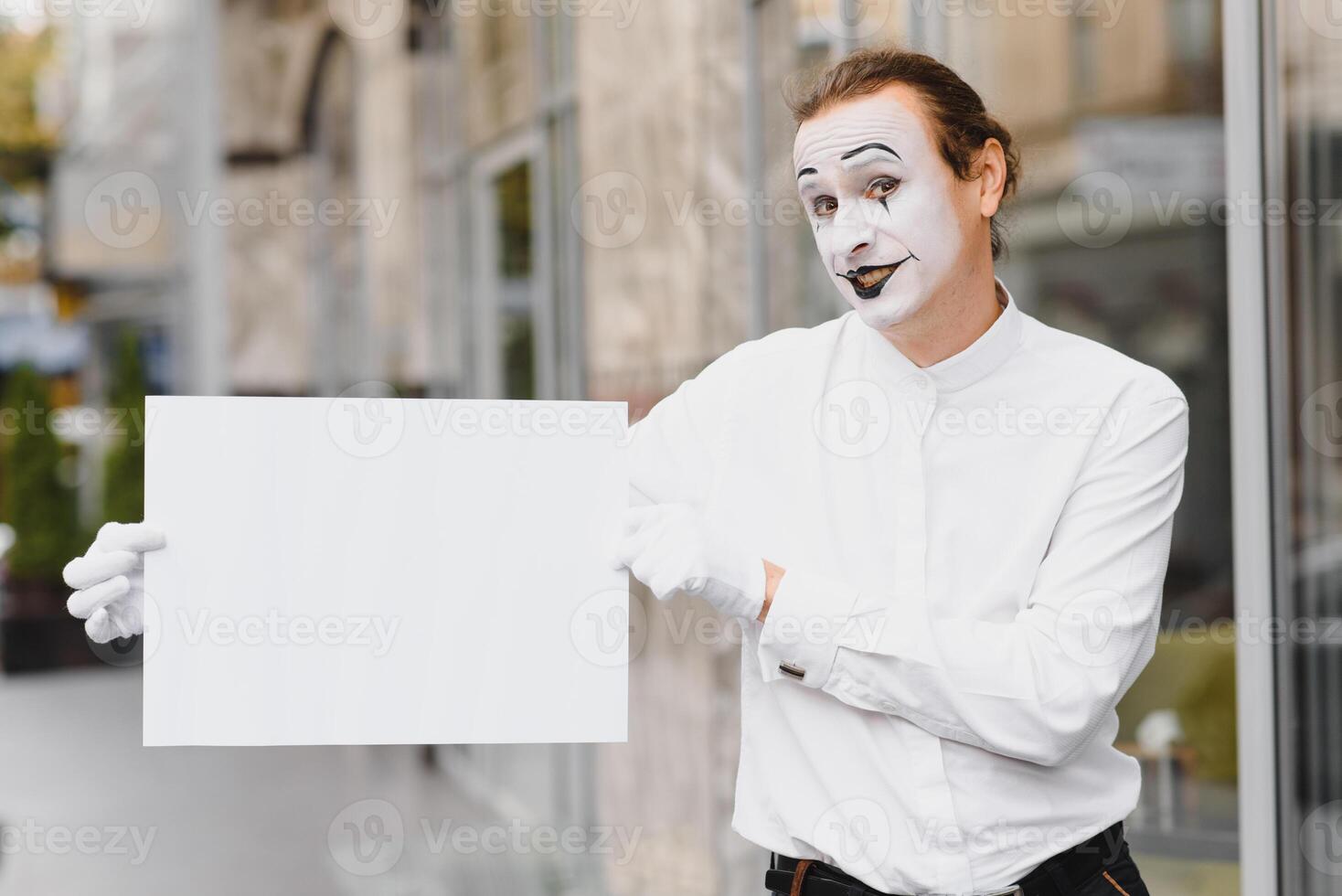 Your text here. Actor mime holding empty white letter. Colorful portrait with gray background. April fools day photo