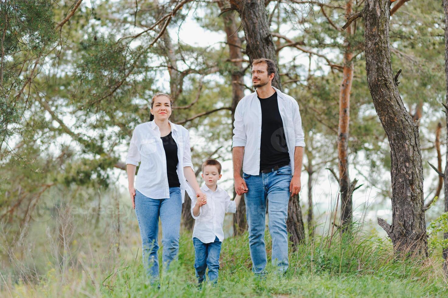 Mom, dad and son walk in the green grass. Happy young family spending time together, running outside, go in nature, on vacation, outdoors. The concept of family holiday. photo