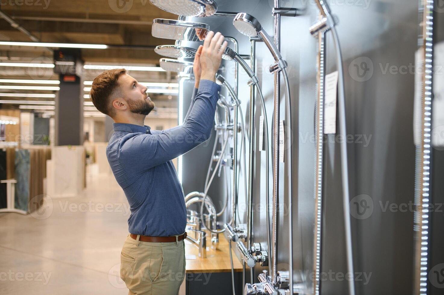 Playing with shower faucet. Man chooses a products in a sanitary ware store photo