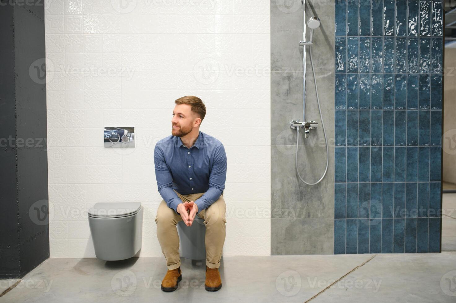 Man sitting on toilet in plumber store photo