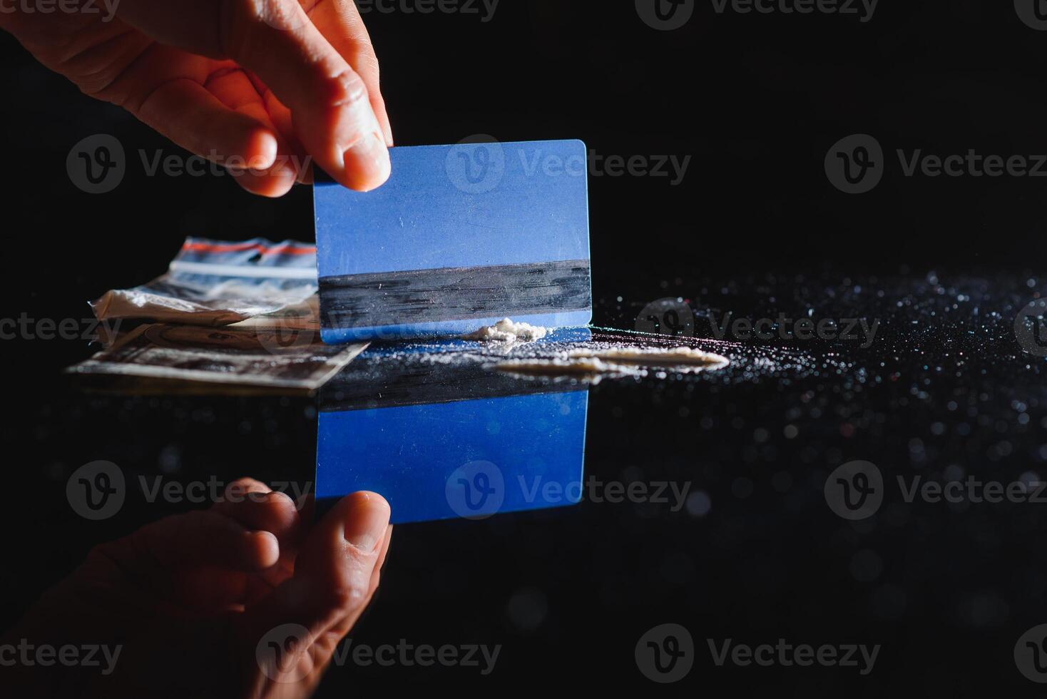 Close up of hands of young druggie is doing tracks of cocaine with a credit card. photo