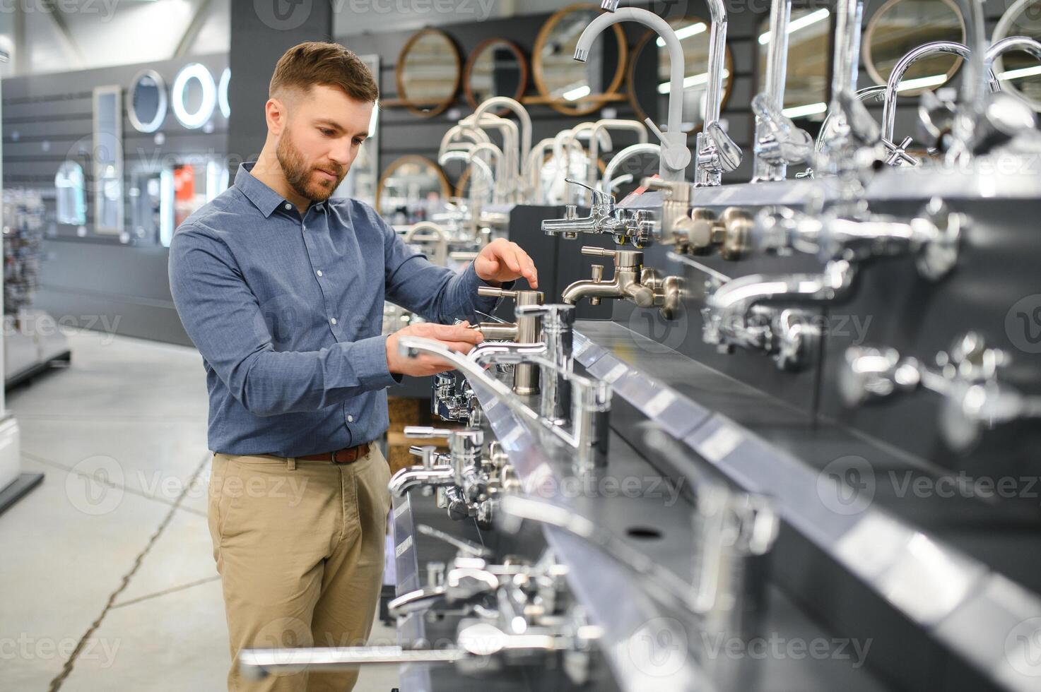A large selection of water faucets. Man chooses a products in a sanitary ware store photo