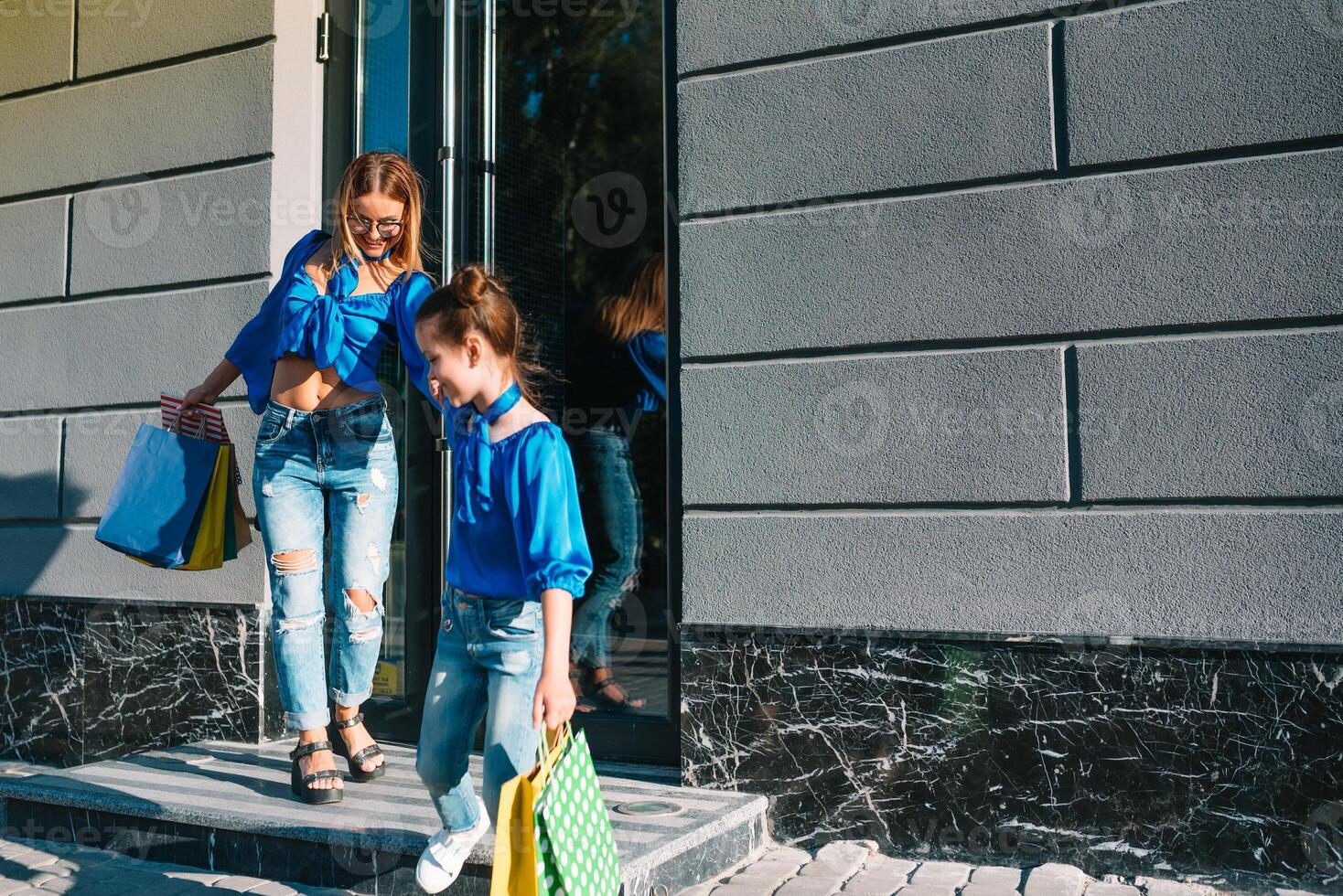 sale, consumerism and people concept - happy young women her dauther with shopping bags walking city street photo