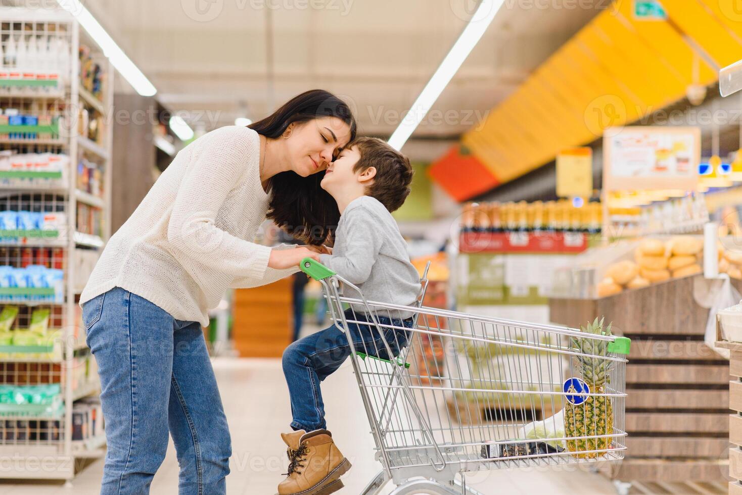 woman and child boy during family shopping with trolley at supermarket photo