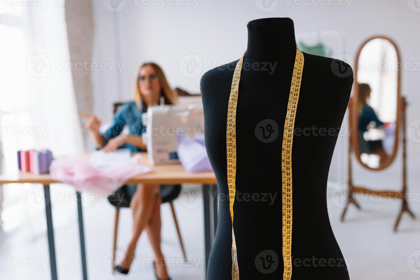 atractivo hembra Moda diseñador es trabajando en su taller. elegante mujer en proceso de creando nuevo ropa colección foto