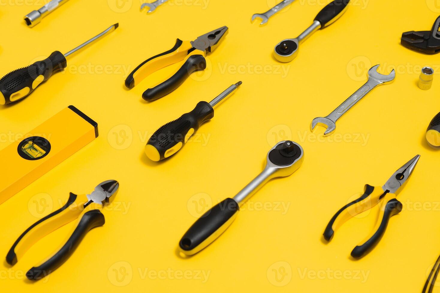 Yellow and black handy tools pilers and screwdriver isolated on yellow background. photo