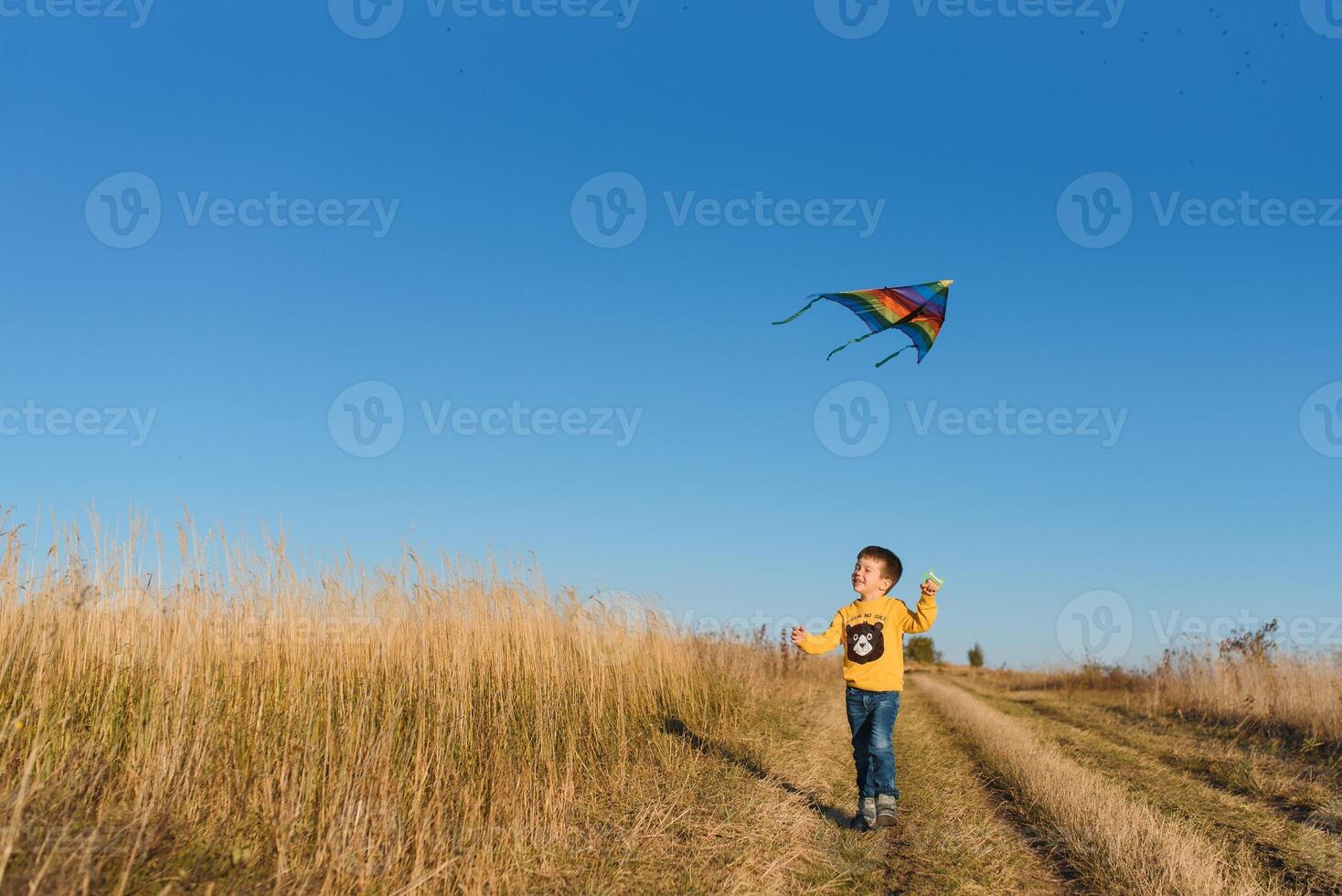 Little boy with kite flying over his head photo
