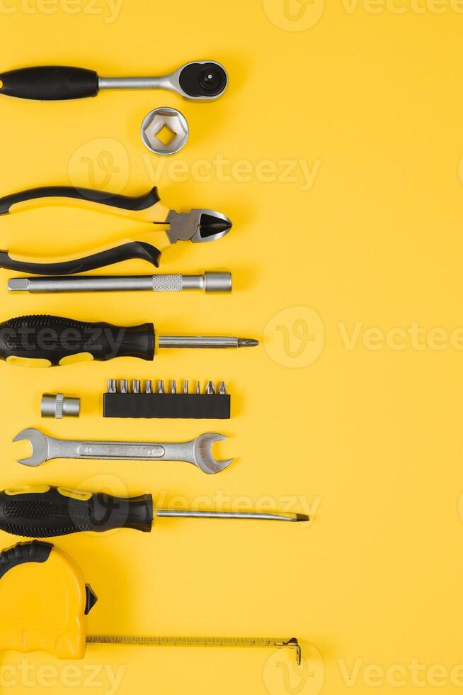 Tools top view on yellow background. Plier, open wrenches, screwdrivers and staple gun flat lay with copy space photo