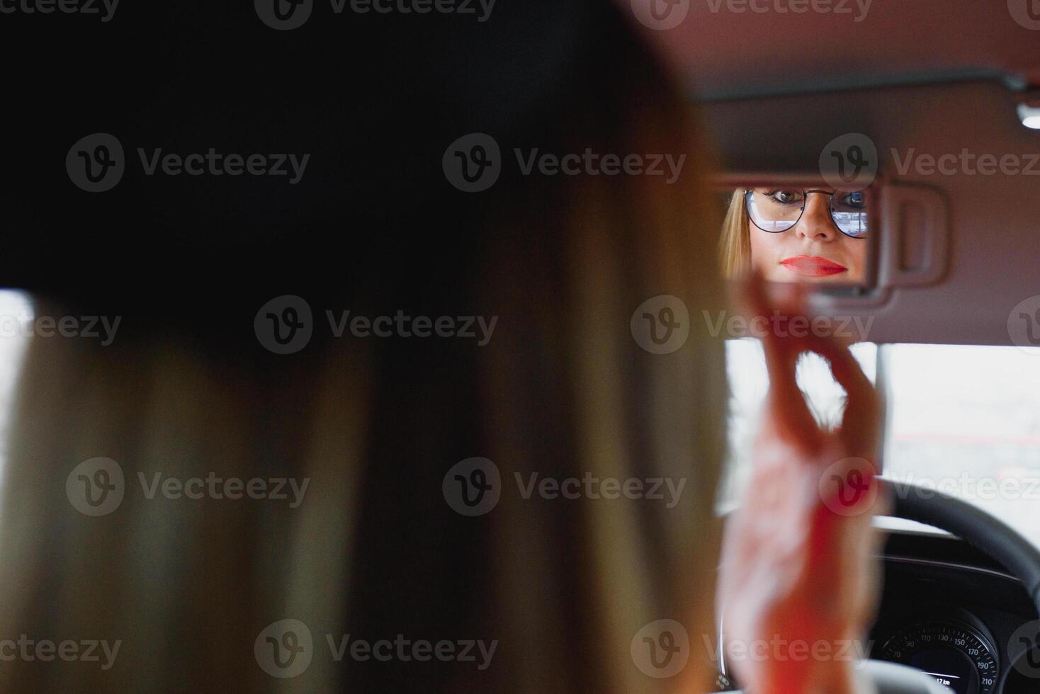 young woman looking in the rearview mirror of a car photo