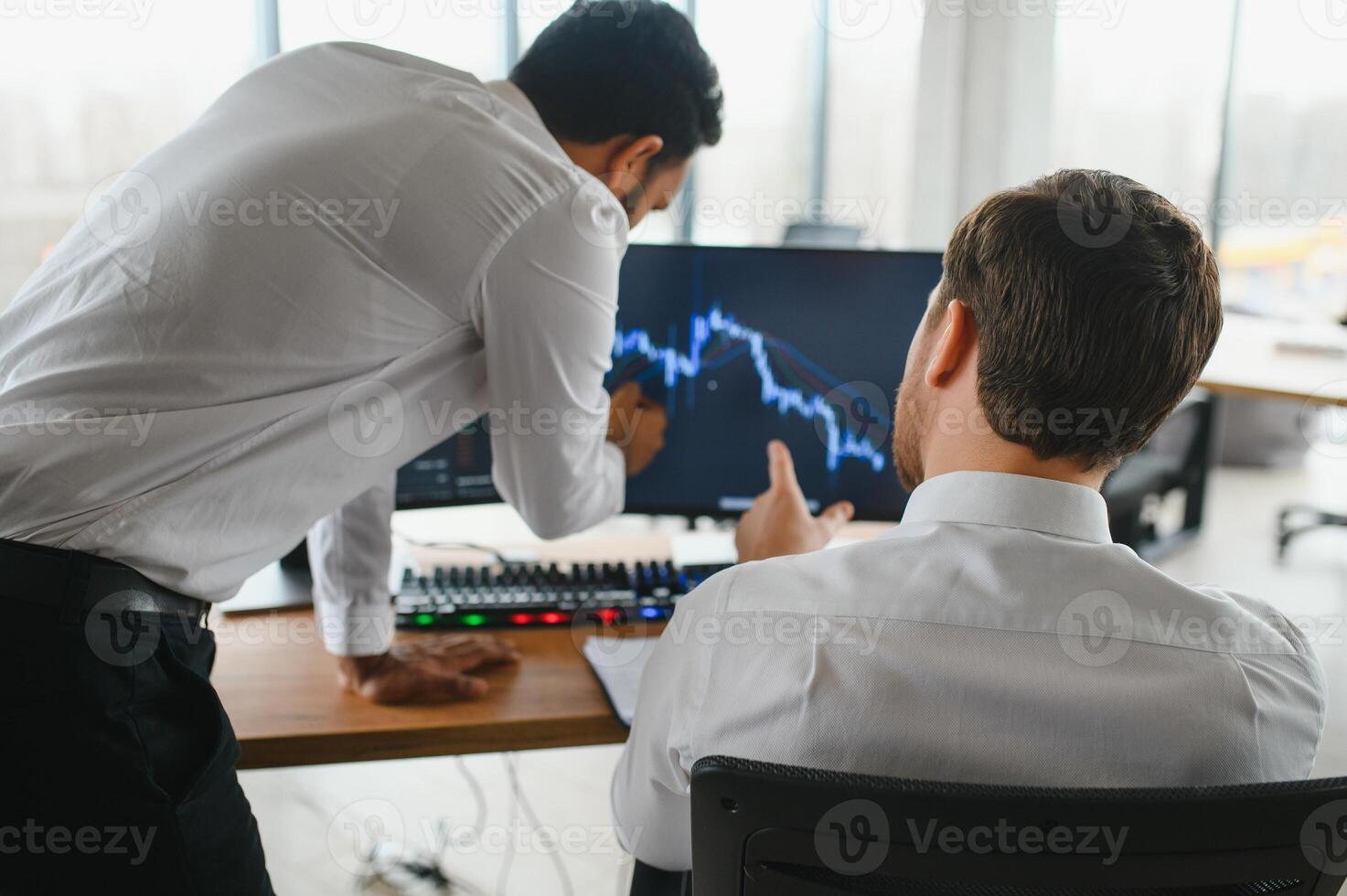 Two men traders sitting at desk at office together looking at data analysis discussing brainstorming successful strategy inspired teamwork concept close-up photo