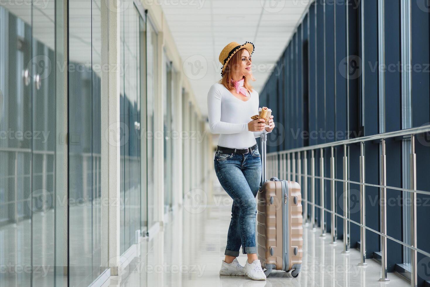 Young pretty stylish woman with luggage at the international airport. Waiting her flight at tax free shopping zone. photo