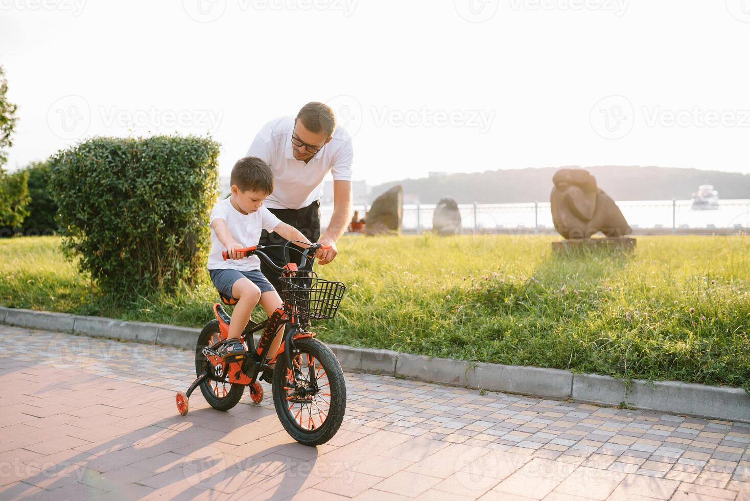 joven y contento padre enseña su joven hijo a paseo un bicicleta. el niño es contento . padre acecho hijo. del padre día. foto