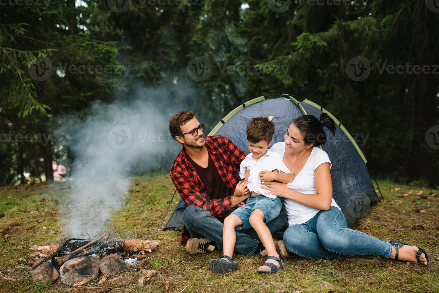 Family near the fire in the forest. Parent with child on a tent background. National Park. Hike with children. Active summer holidays photo
