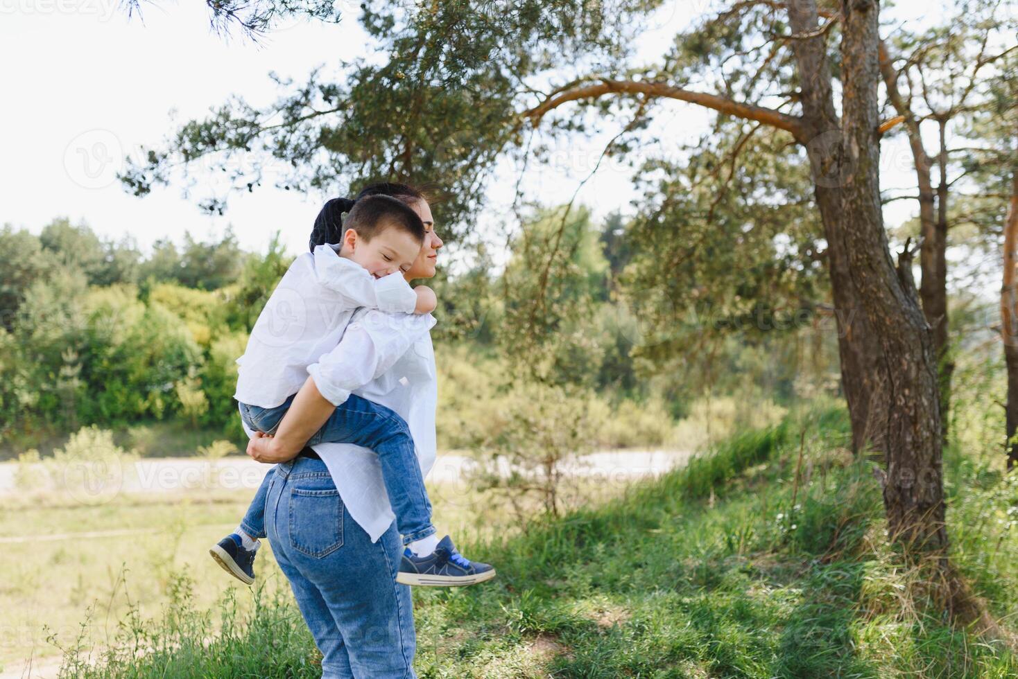 elegante madre y hermoso hijo teniendo divertido en el naturaleza. contento familia concepto. belleza naturaleza escena con familia al aire libre estilo de vida. contento familia descansando juntos. felicidad en familia vida. madres día. foto