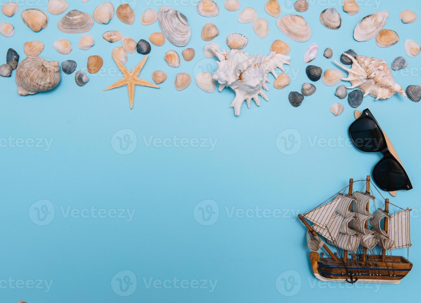 Flat lay. Top view. Frame of shells of various kinds on a blue background. Seashells and starfish on a pastel background. Vacation concept. travel concept. with copy space photo