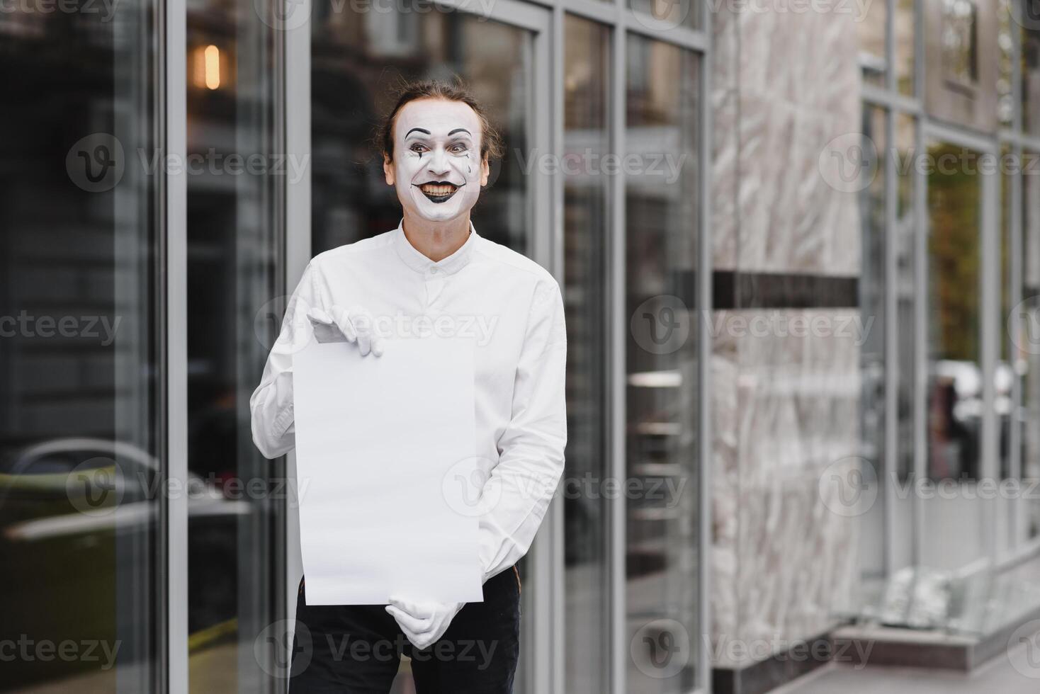 Your text here. Actor mime holding empty white letter. Colorful portrait with gray background. April fools day photo