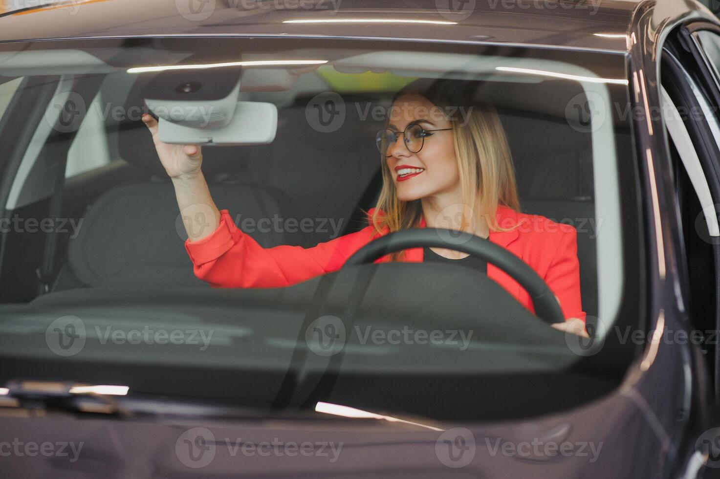 young woman looking in the rearview mirror of a car photo