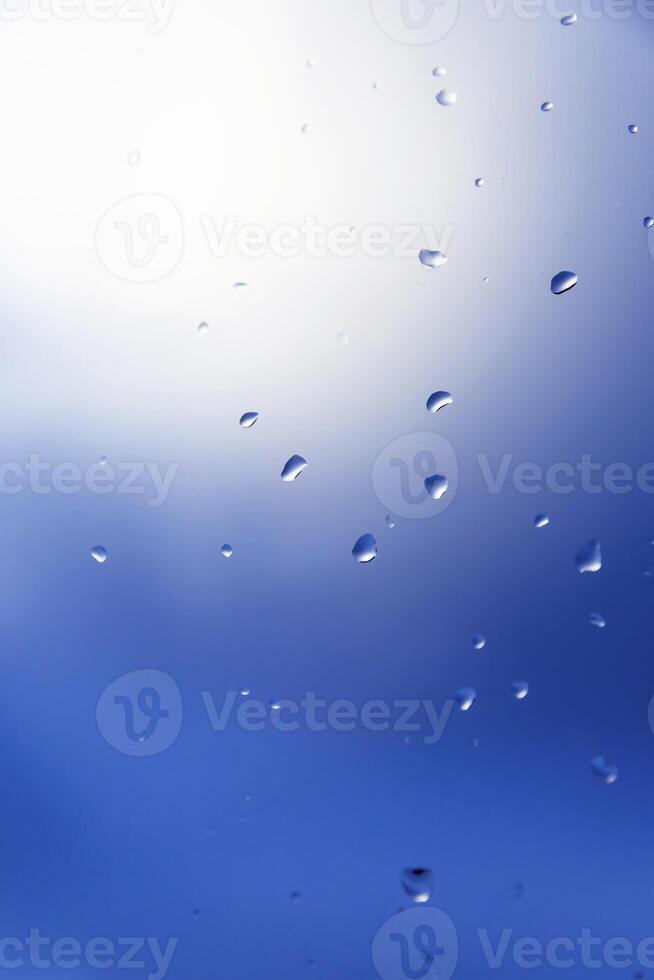 macro photography of raindrops on window with blue background photo