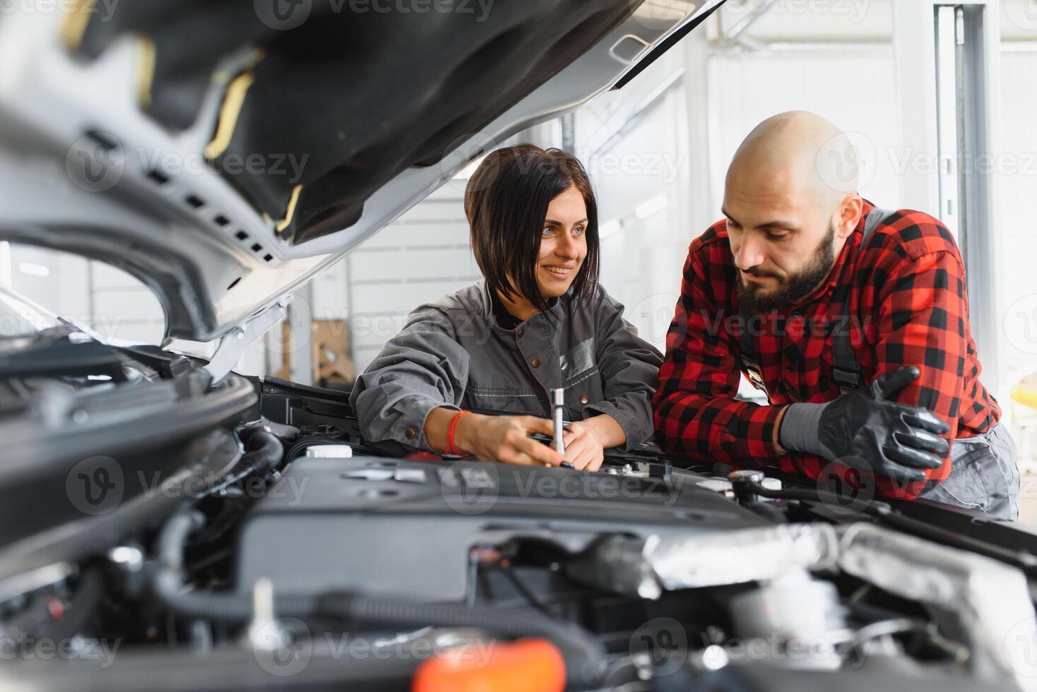Auto car repair service center. Mechanic examining car engine. Female Mechanic working in her workshop. Auto Service Business Concept. Pro Car female Mechanic Taking Care of Vehicle. photo
