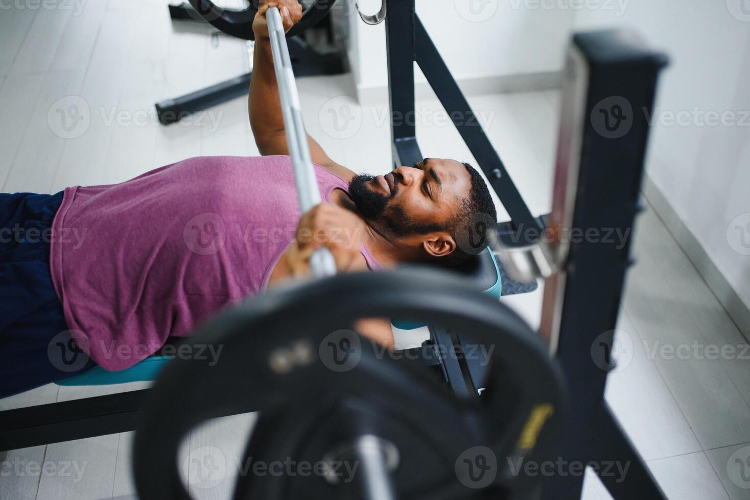 Weight lifter at the bench press lifting a barbell on an bench. photo
