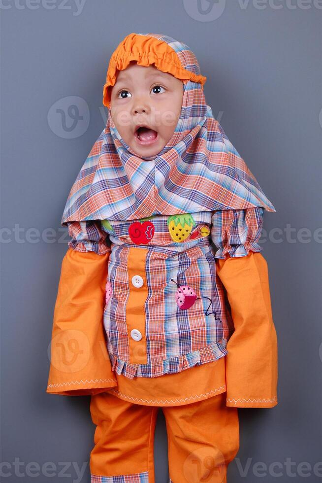 un indonesio pequeño niña vistiendo hijab paño muy emocionado foto