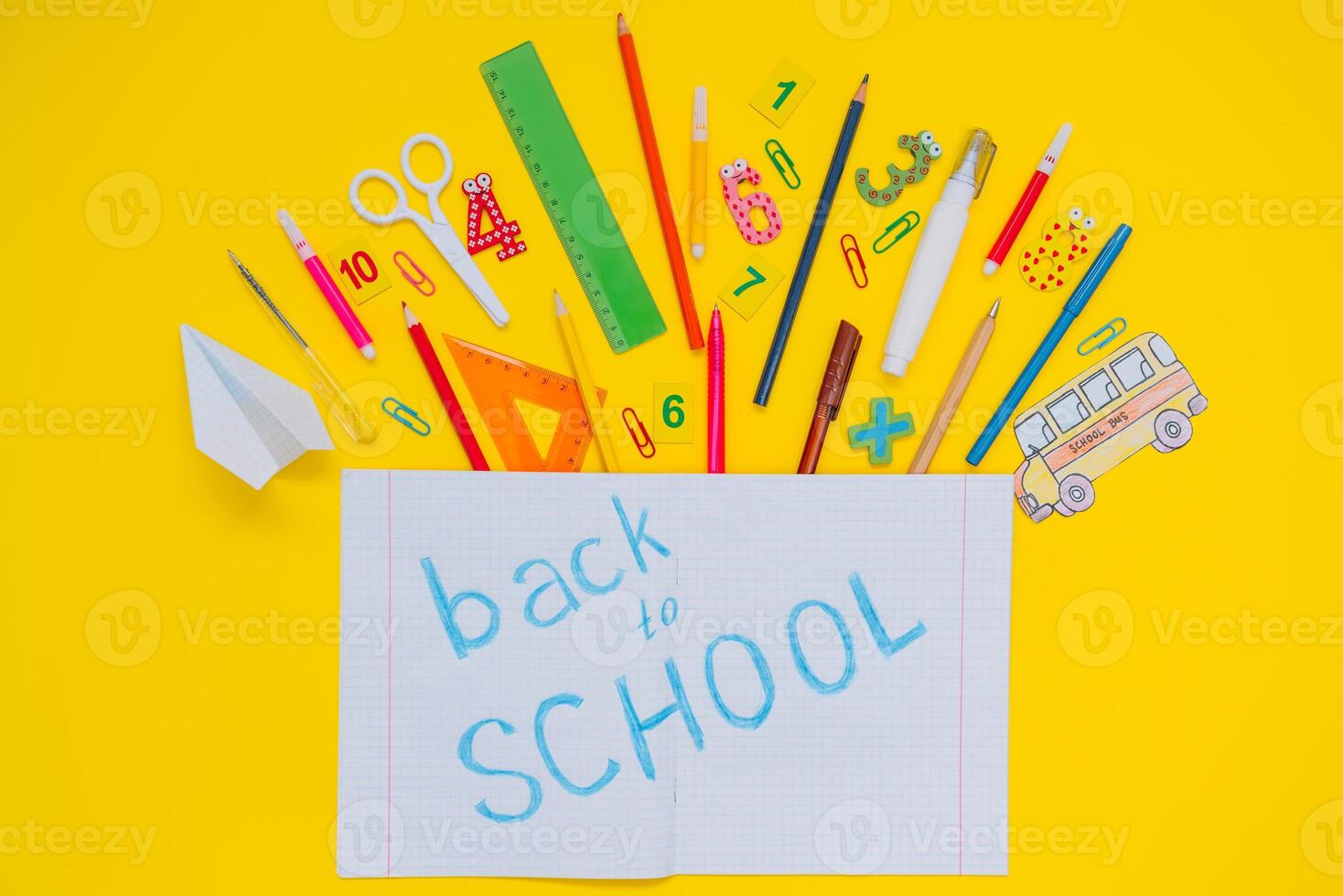 School notebook and stationery over yellow desk. Back to school abstract background. School equipment. Variety of school supplies. Flat lay photo