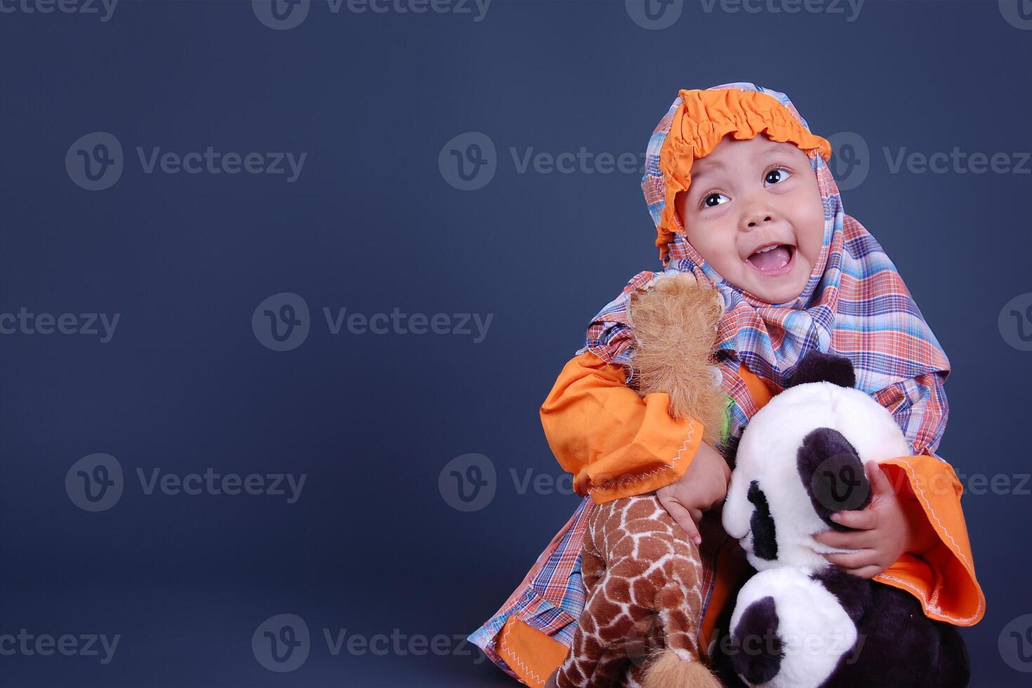 An Indonesian little girl wearing hijab cloth while holding her lovely doll photo