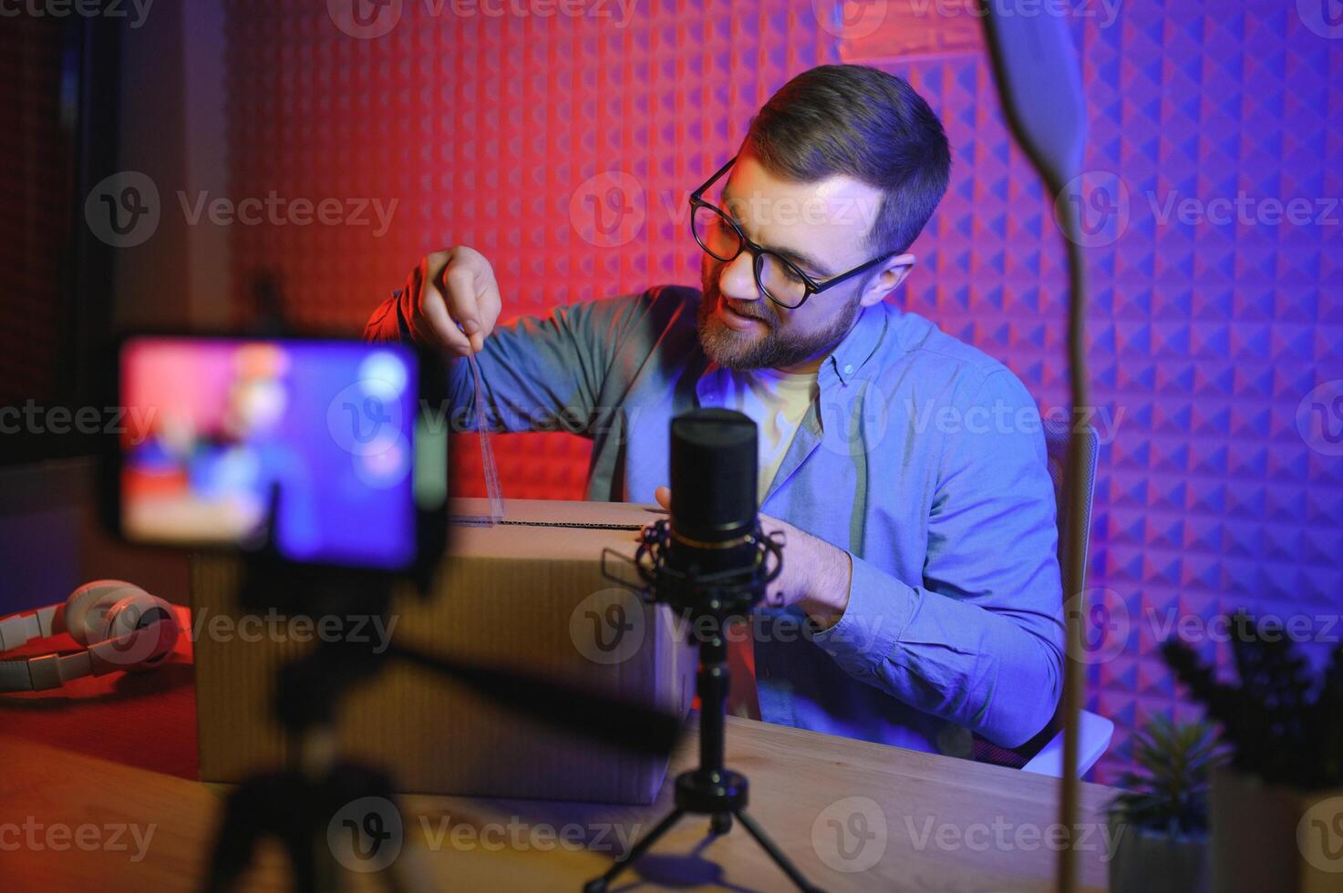 Handsome young man gesturing while unpacking parcel, excited, clenches fists in triumph. Joyful male vlogger. Concept of people and social networks. photo