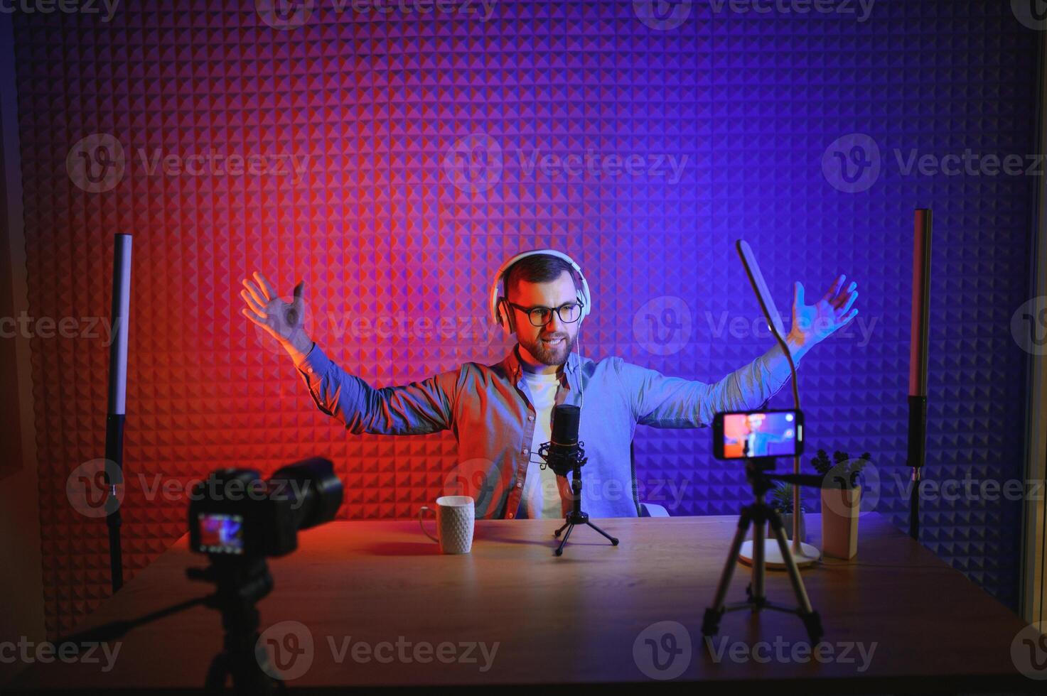 vlogger using smartphone to film podcast in studio. blogger with mobile phone, microphone and headphones filming video for social media broadcasting career. photo