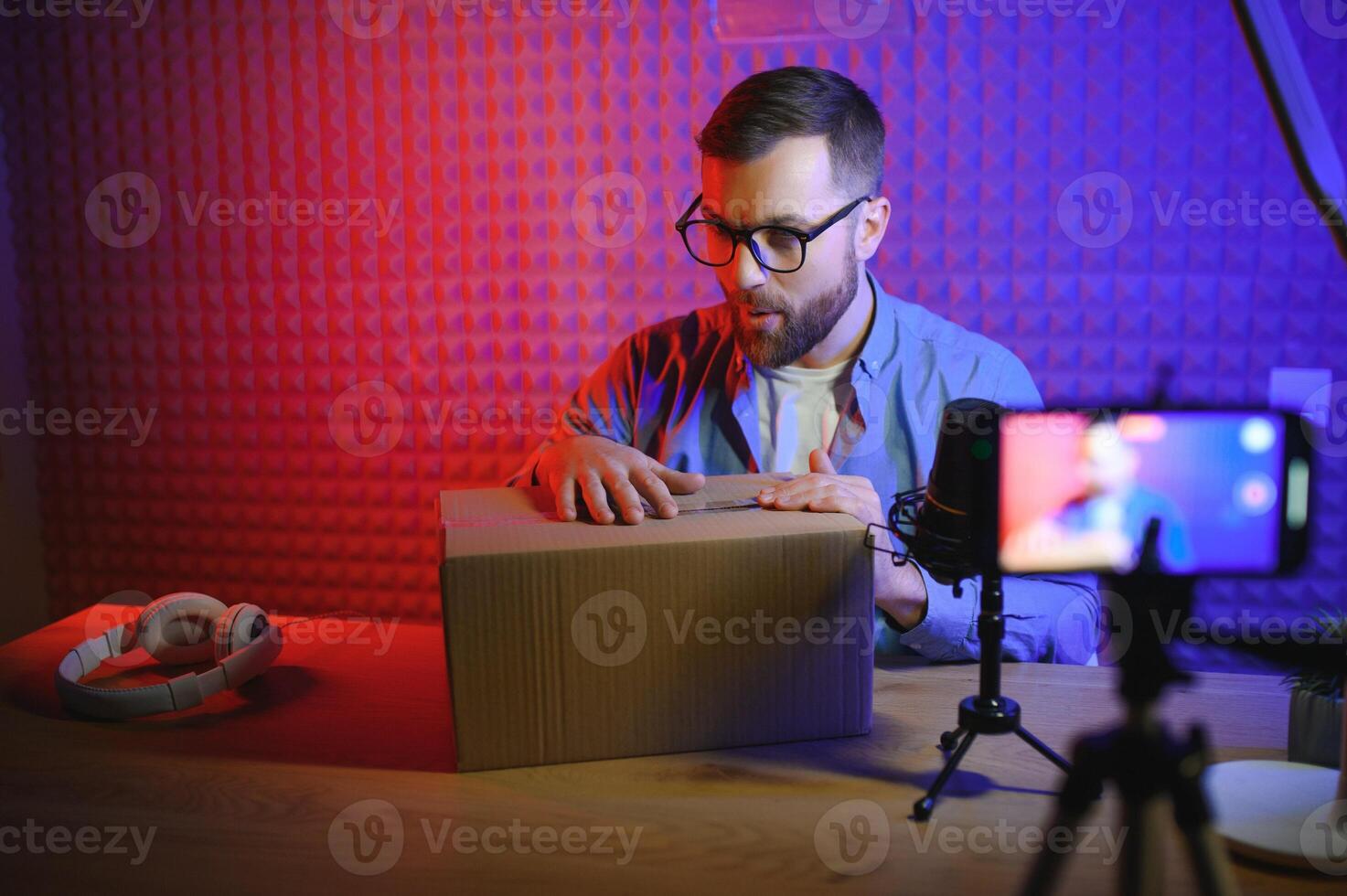 vlogger using smartphone to film podcast in studio. blogger with mobile phone, microphone and headphones filming video for social media broadcasting career. photo