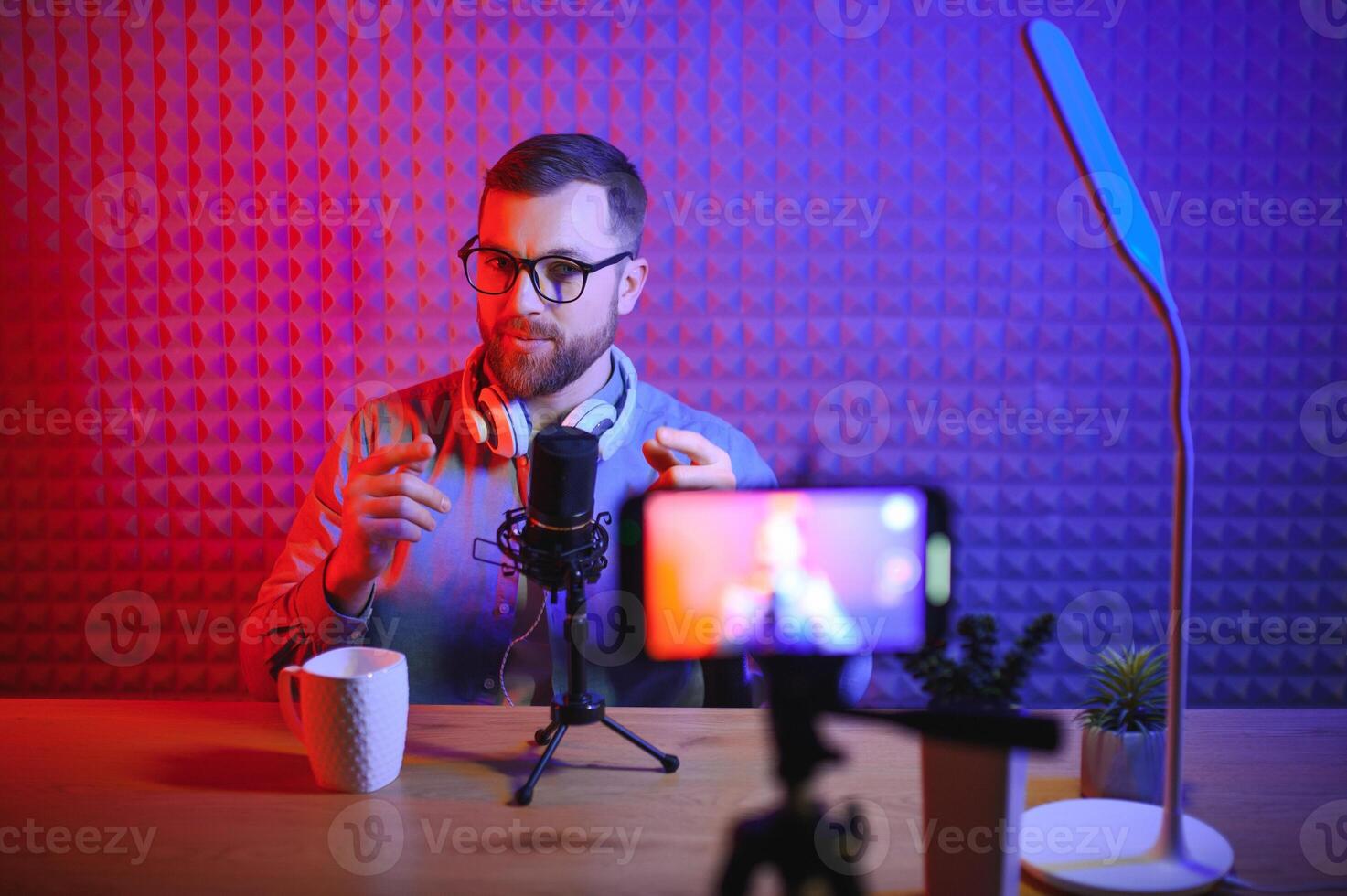 Young man recording or streaming podcast using microphone at his small broadcast studio. Content creator. photo