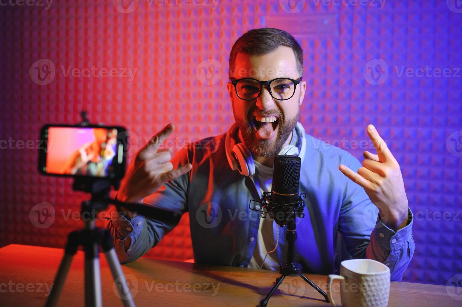 joven hombre grabación o transmisión podcast utilizando micrófono a su pequeño transmitir estudio. contenido creador. foto