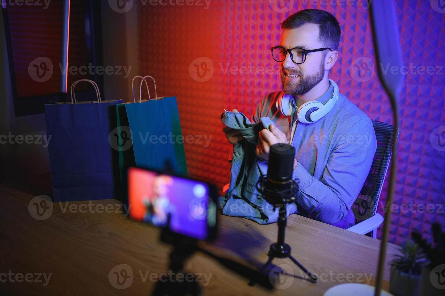 Young man recording or streaming podcast using microphone at his small broadcast studio. Content creator. photo