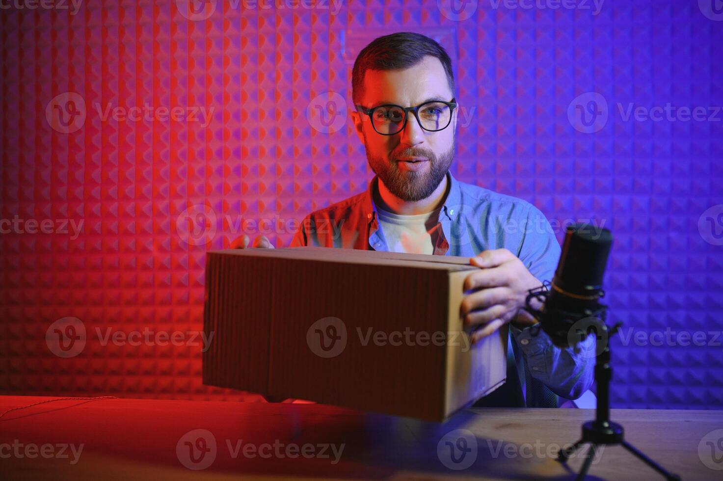 Young man recording or streaming podcast using microphone at his small broadcast studio. Content creator. photo