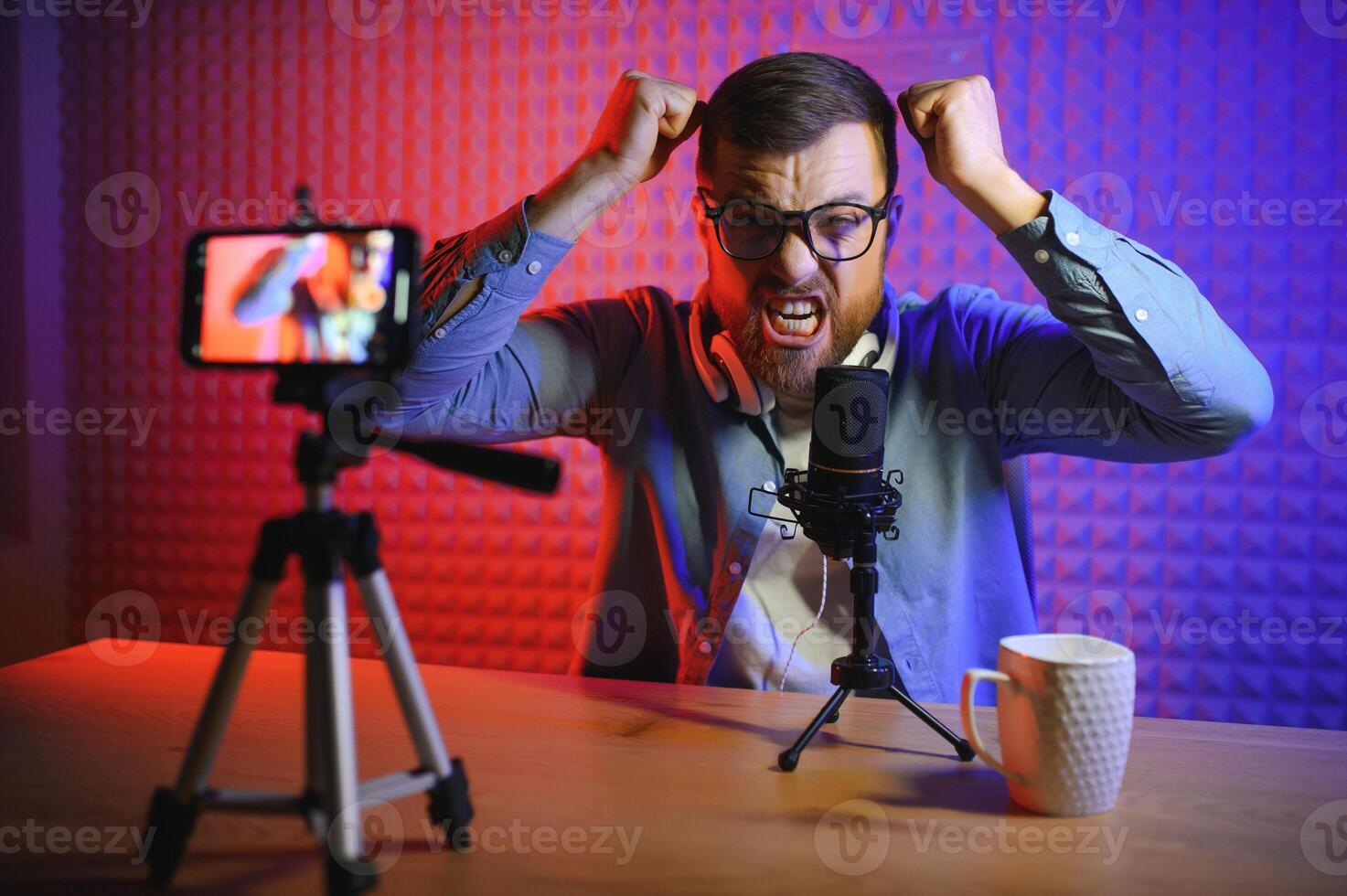 Young man recording or streaming podcast using microphone at his small broadcast studio. Content creator. photo