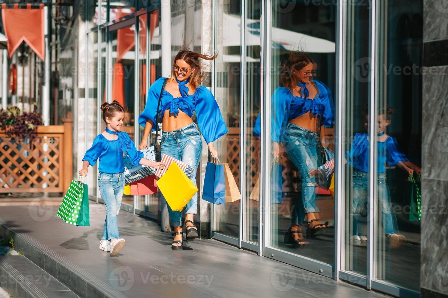 sale, consumerism and people concept - happy young women her dauther with shopping bags walking city street photo